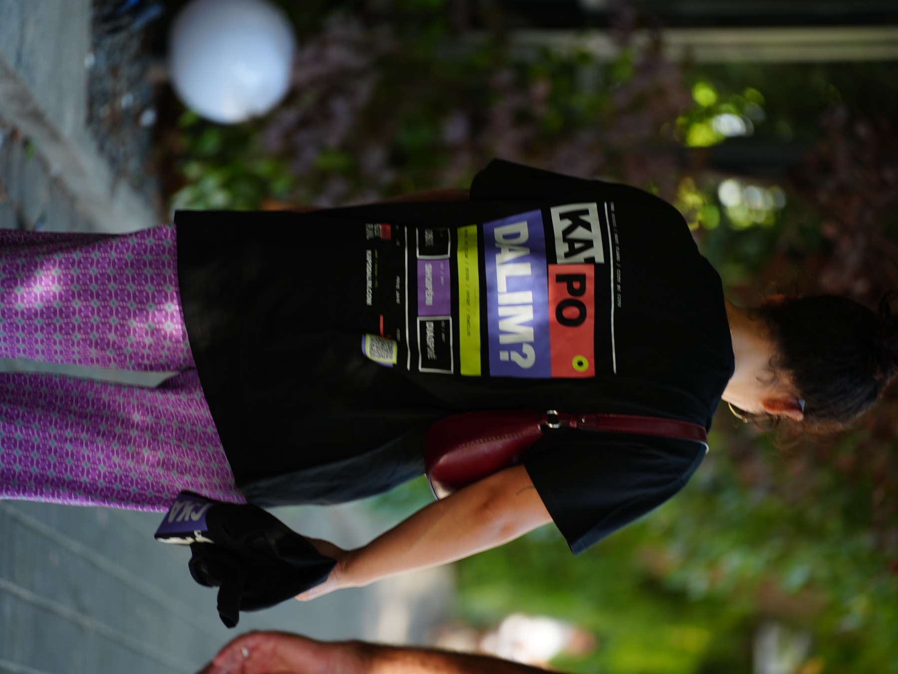 Woman walking in the street with the back print of the RRUGA 01 T-shirt