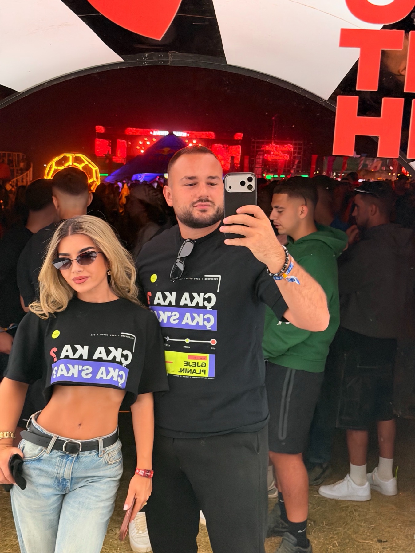 Two people wearing the RRUGA 01 T-shirt in front of a mirror at Sunny Hill